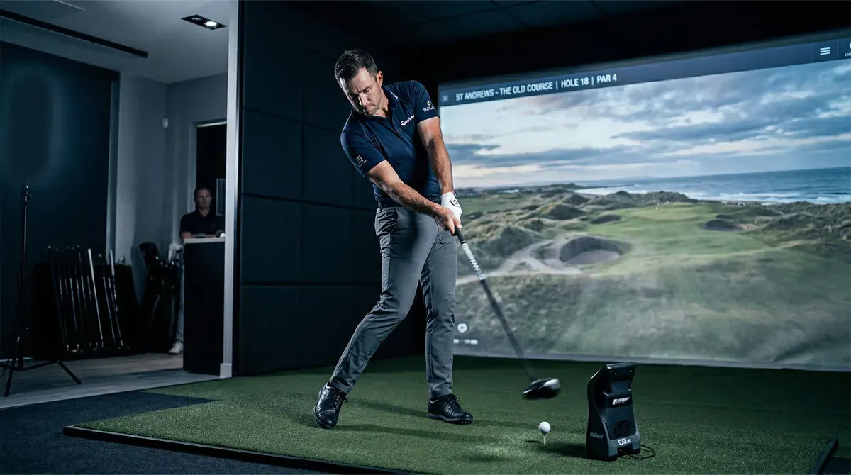 Golfer mid-swing at an Avus simulator